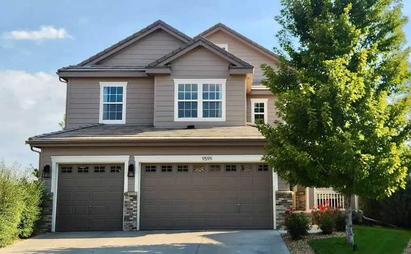 Repainted taupe two-story home with white trim and dual garage in Aurora